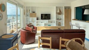 En stue med fjernsyn, sofa, sofabord og havudsigt.