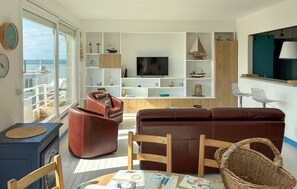 Ein Wohnzimmer mit Fernseher, einer Couch, einem Couchtisch und Meerblick.