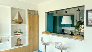 Et moderne køkken med et træskab, en hængende lampe, et spejl og to barstole.