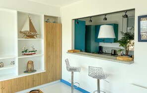 Eine moderne Küche mit einem Holzkasten, einer Hängelampe, einem Spiegel und zwei Barhocker.