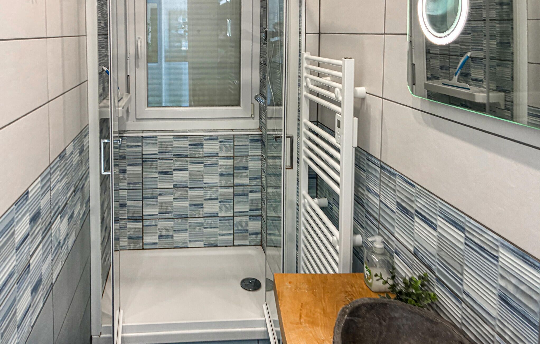 Une salle de bain équipée d’une douche, de toilettes, d’un lavabo et d’un miroir.