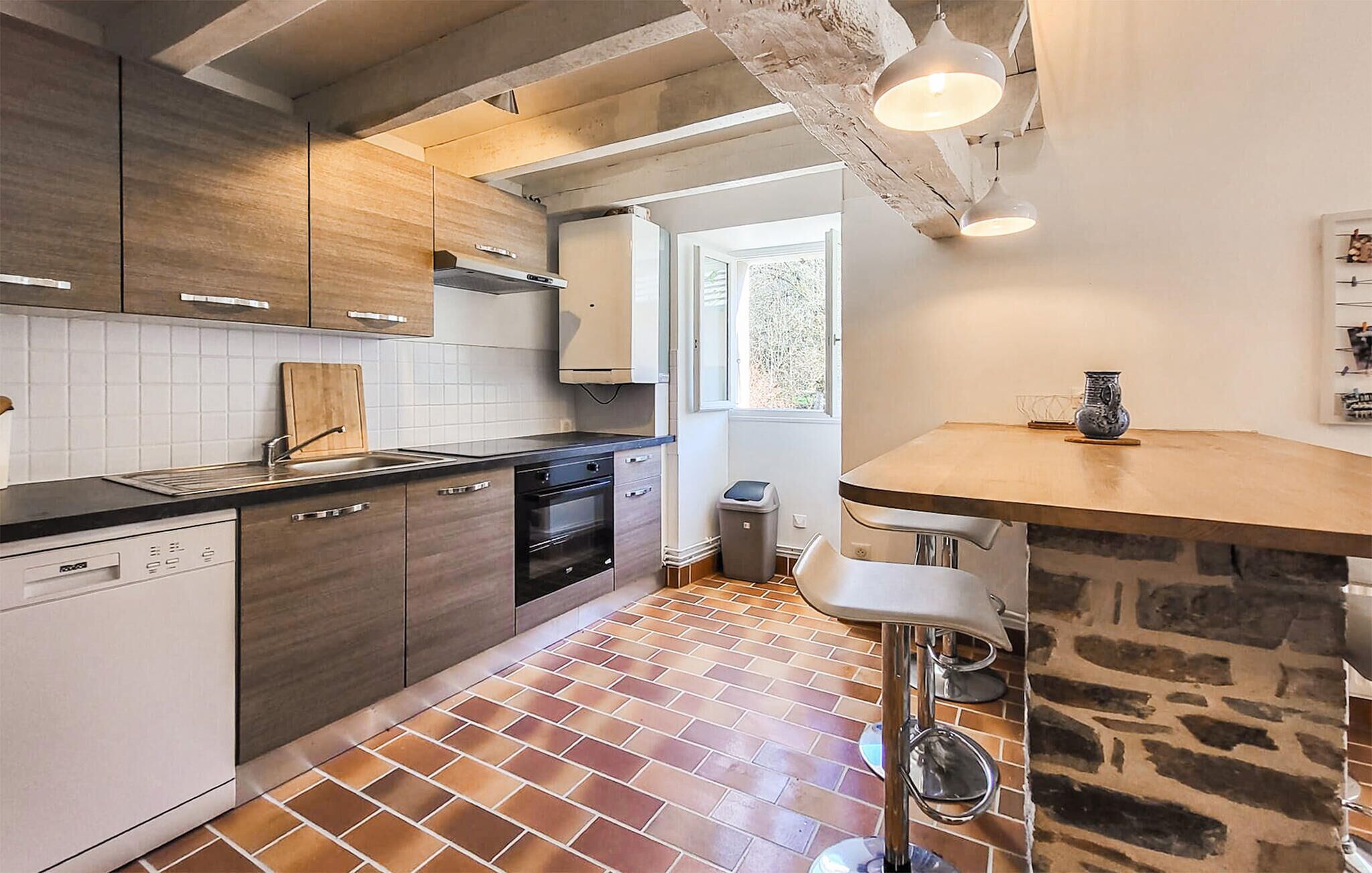 A modern kitchen with a dishwasher, oven, and a stone accent wall.