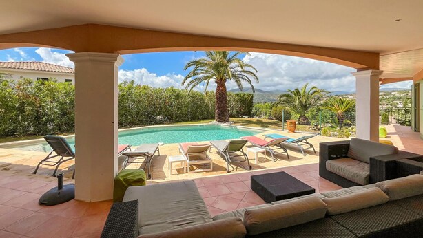 Ein überdachter Außenbereich mit Pool, Liegestühlen und einer Sitzecke.