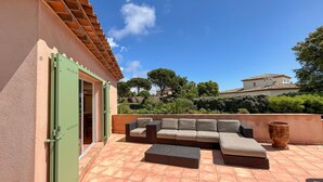 Eine Außenpatio mit einer Couch, einem großen Pflanztopf und einer grünen Tür.