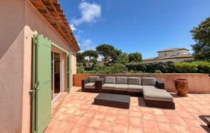 Eine Außenpatio mit einer Couch, einem großen Pflanztopf und einer grünen Tür.