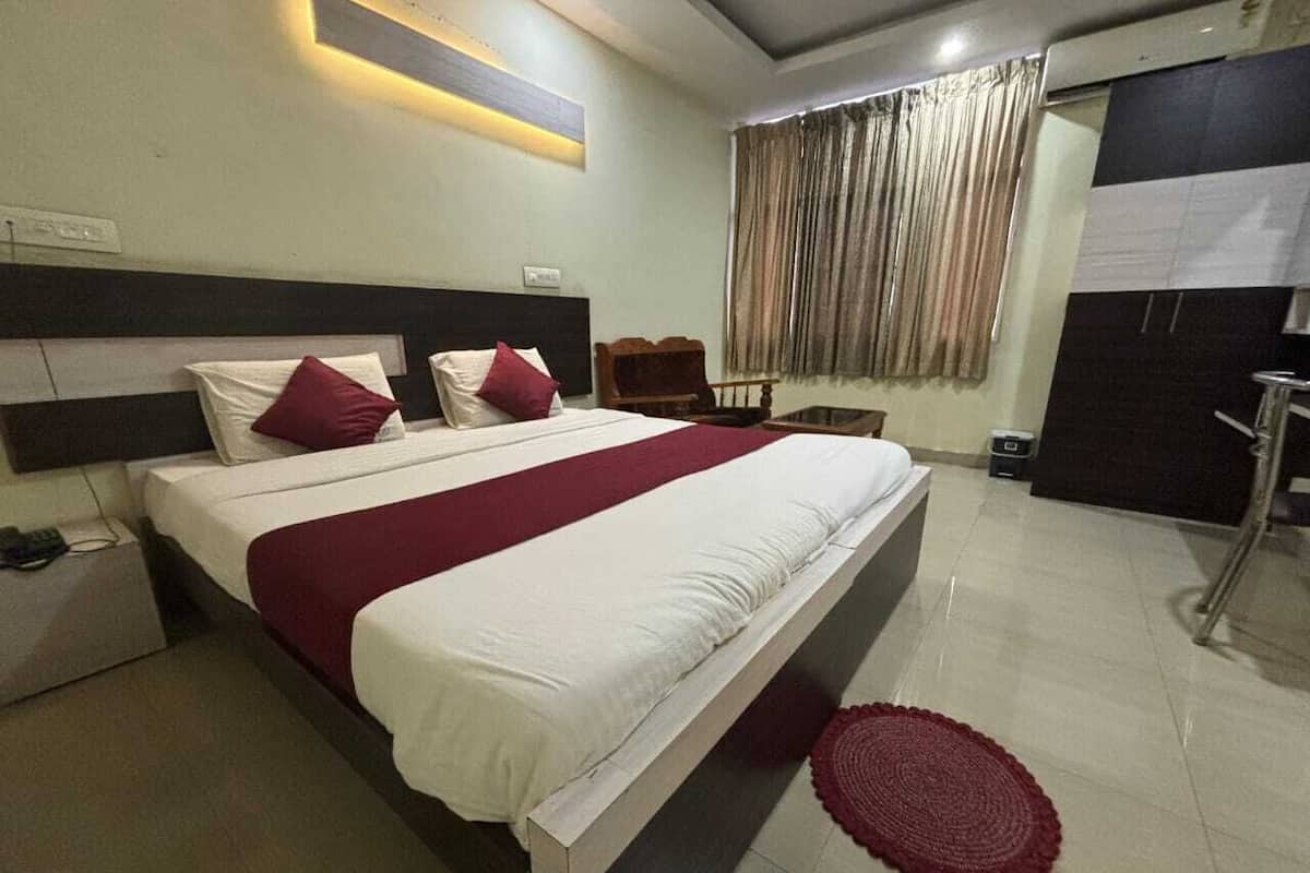 A hotel room with a large bed, a bedside table, a wardrobe, and a window with curtains.