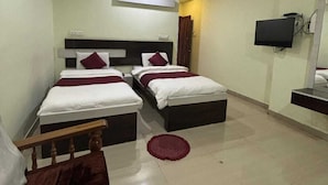 A hotel room with two beds, a ceiling fan, a TV, and a small rug. - Hotel Cityleaf (Shimoga)