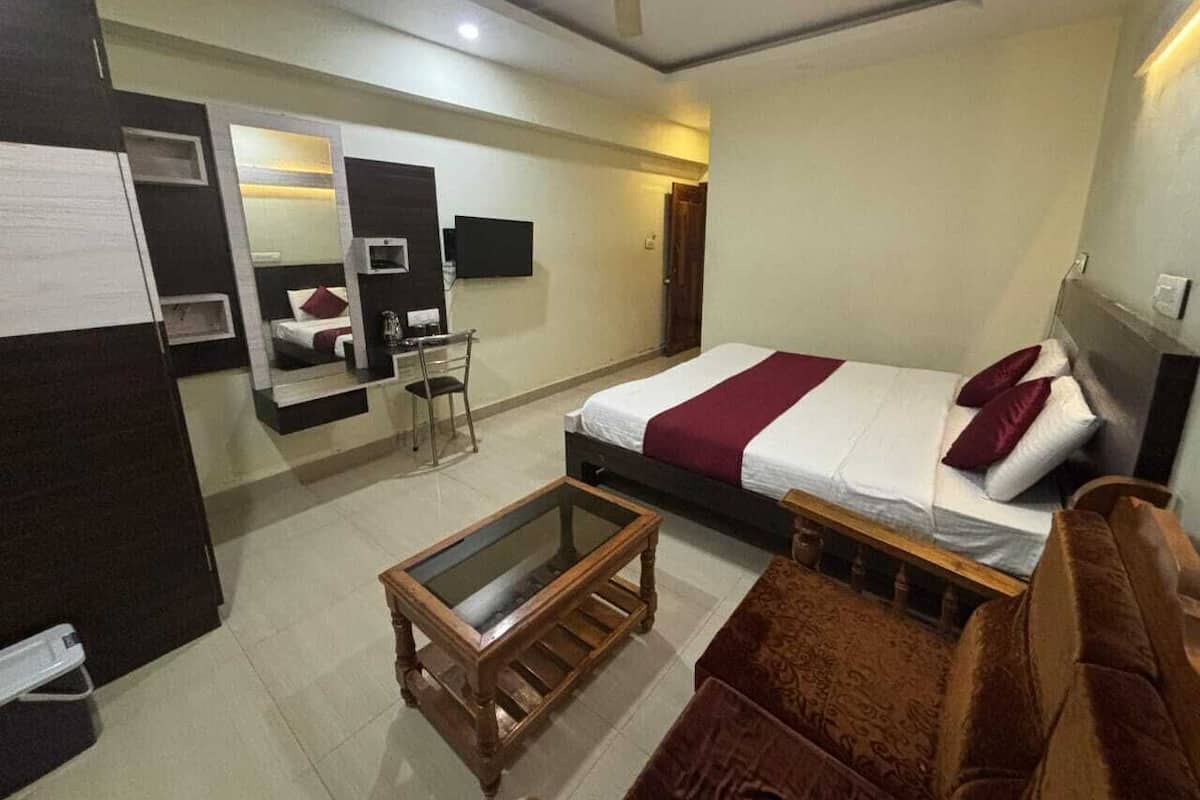 A hotel room with a bed, a desk, a chair, a small table, and a ceiling fan.