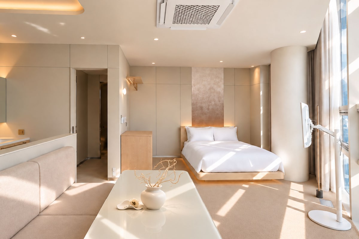 Een moderne hotelkamer met een bed, nachtkastje en een groot raam.