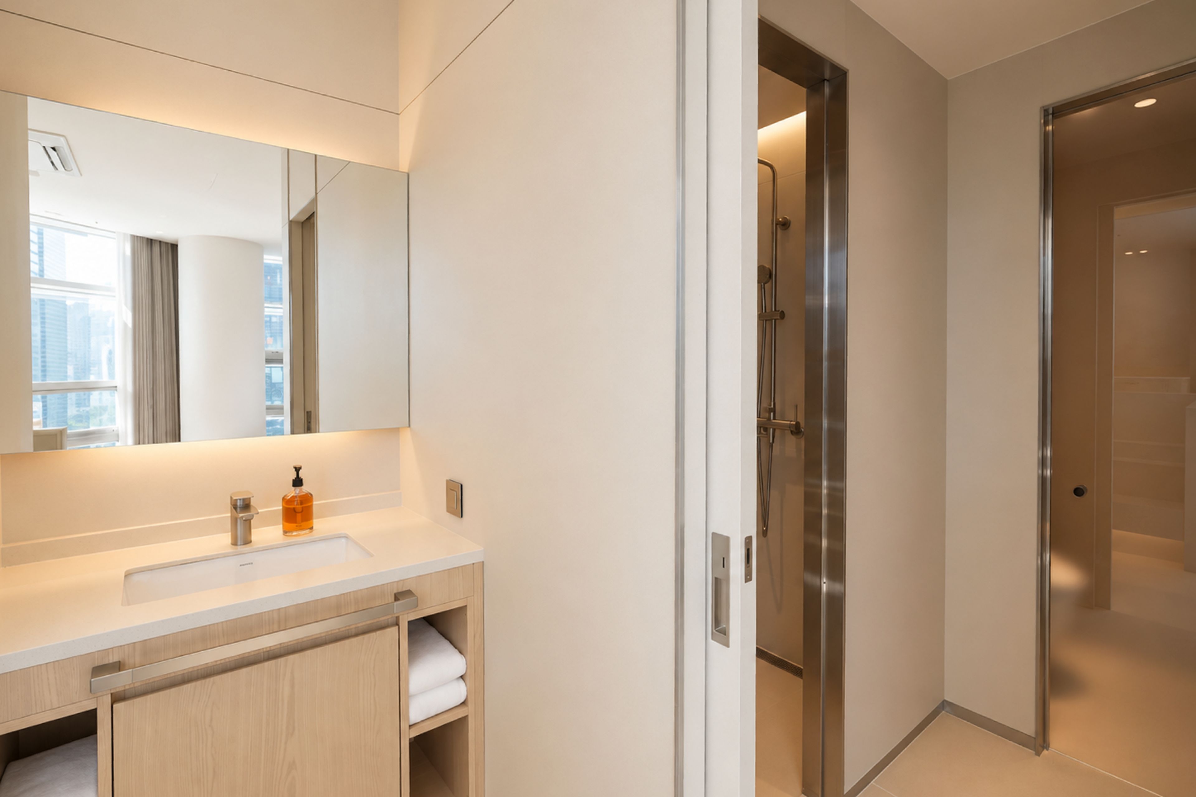 A modern bathroom with a large mirror, a sink, and a shower area.
