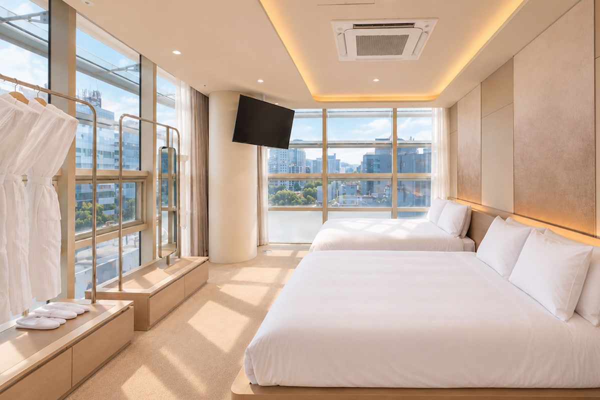 Een hotelkamer met een groot bed, een aan de muur bevestigde televisie en uitzicht op de stad.