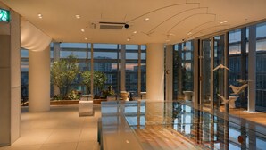 Ein modernes Interieur mit großen Fenstern, einer Glastrennwand und Zimmerpflanzen.