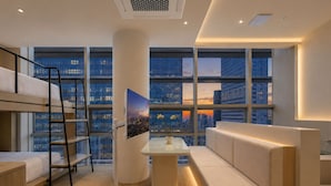 A modern hotel room with a bunk bed, a desk, a sofa, and large windows offering city views. - UH Suite Seoul Insadong (Seoul)
