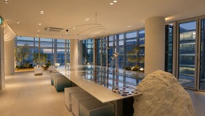 Ein modernes Interieur mit einem langen, spiegelnden Tisch, Sitzgelegenheiten und großen Fenstern mit Blick auf die Stadt.
