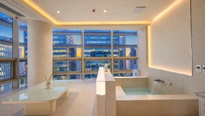 Ein modernes Hotelzimmer mit großem Fenster, einer Badewanne und einem Glastisch.