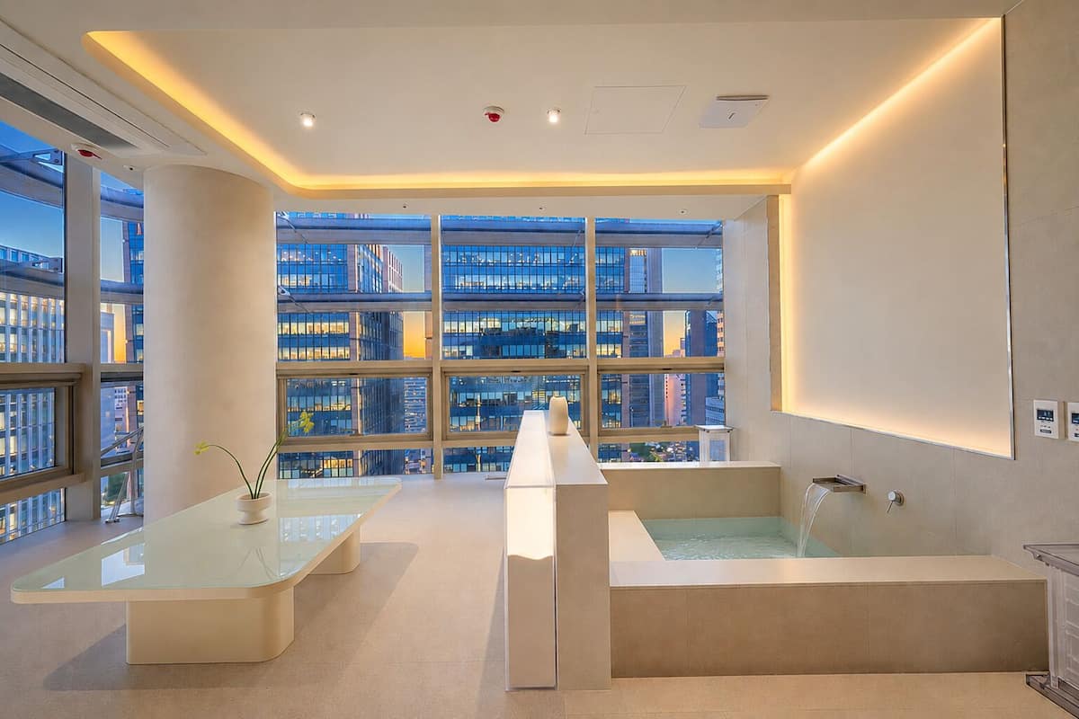 Una habitación de hotel moderna con un ventanal grande, una bañera y una mesa de vidrio.