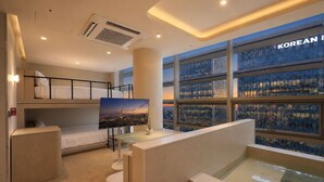 A modern hotel room with bunk beds, a flat-screen TV, a glass table, and a city view. - UH Suite Seoul Insadong (Seoul)