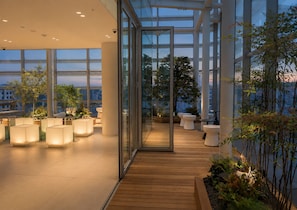 A modern indoor space with glass walls, wooden flooring, and potted plants.