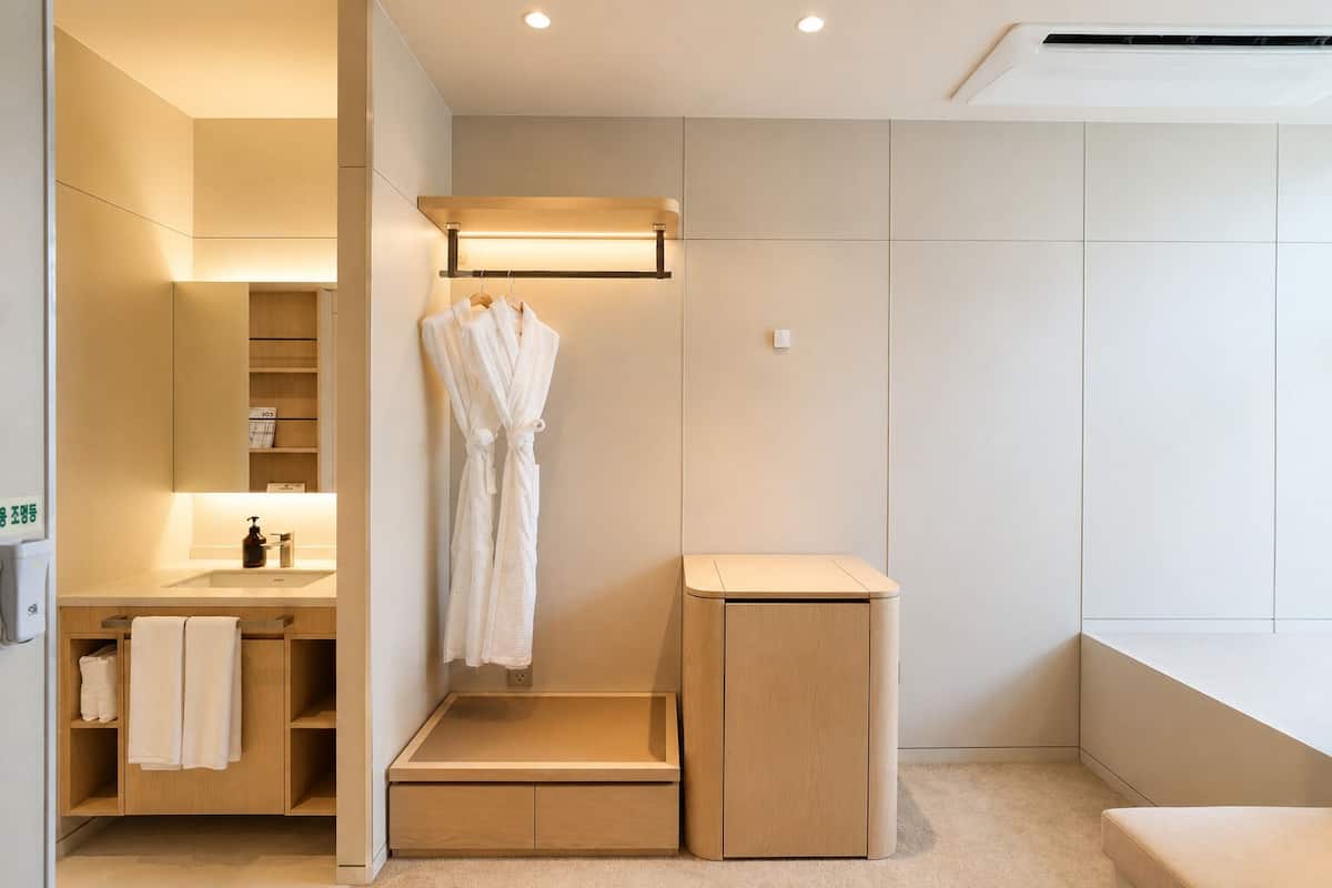 Un baño moderno con ducha, tocador con lavamanos y perchero para toallas.