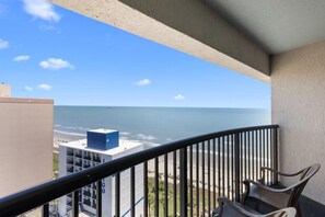 Ein Balkon mit Blick auf den Ozean, ein Stuhl und ein Gebäude mit der Aufschrift 'GOGO'.