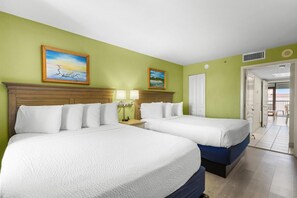Ein Hotelzimmer mit zwei Betten, einem hölzernen Kopfteil, einem Nachttisch mit Lampe und zwei Bildern an der Wand.