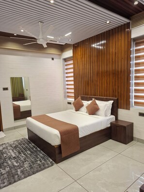 A modern bedroom with a large bed, a ceiling fan, and a mirror.