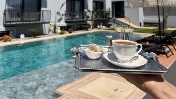 A modern building with balconies, a swimming pool, and outdoor seating. - Çeşme Güzel Life (Cesme)