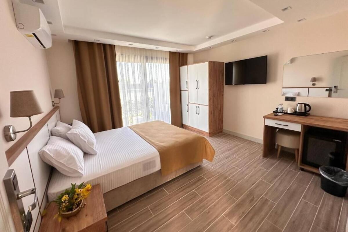 Una habitación de hotel con cama, escritorio, televisor y armario.