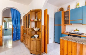 Eine Küche mit Holzausstattung, einem eingebauten Ofen und einer gefliesten Spritzschutzwand.