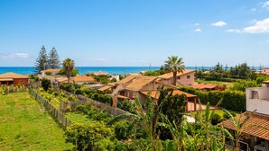 A coastal residential area with houses, a fence, and a clear view of the sea. - 2 bedroom lovely home in Santa Maria del Focall (Santa Maria del Focall)