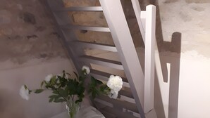 En trappa med vita räcken, ett vitt bord med en vas med blommor och en stenmur.
