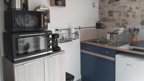 Ett kompakt kök med mikrovågsugn, kaffebryggare och ett litet kylskåp.