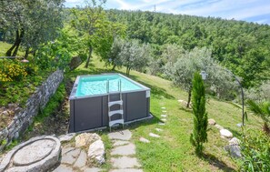 A rectangular outdoor swimming pool with a ladder, surrounded by a stone pathway, set in a lush green landscape with trees and a hill in the background. - Amazing home in Sesto Fiorentino (Sesto Fiorentino)