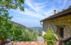 Ein Steinhaus mit rustikalem Dach, einem kleinen Fenster und Blick auf ein Tal.