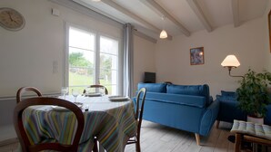 Un coin repas avec une table dressée pour deux personnes, un canapé bleu et une plante en pot.
