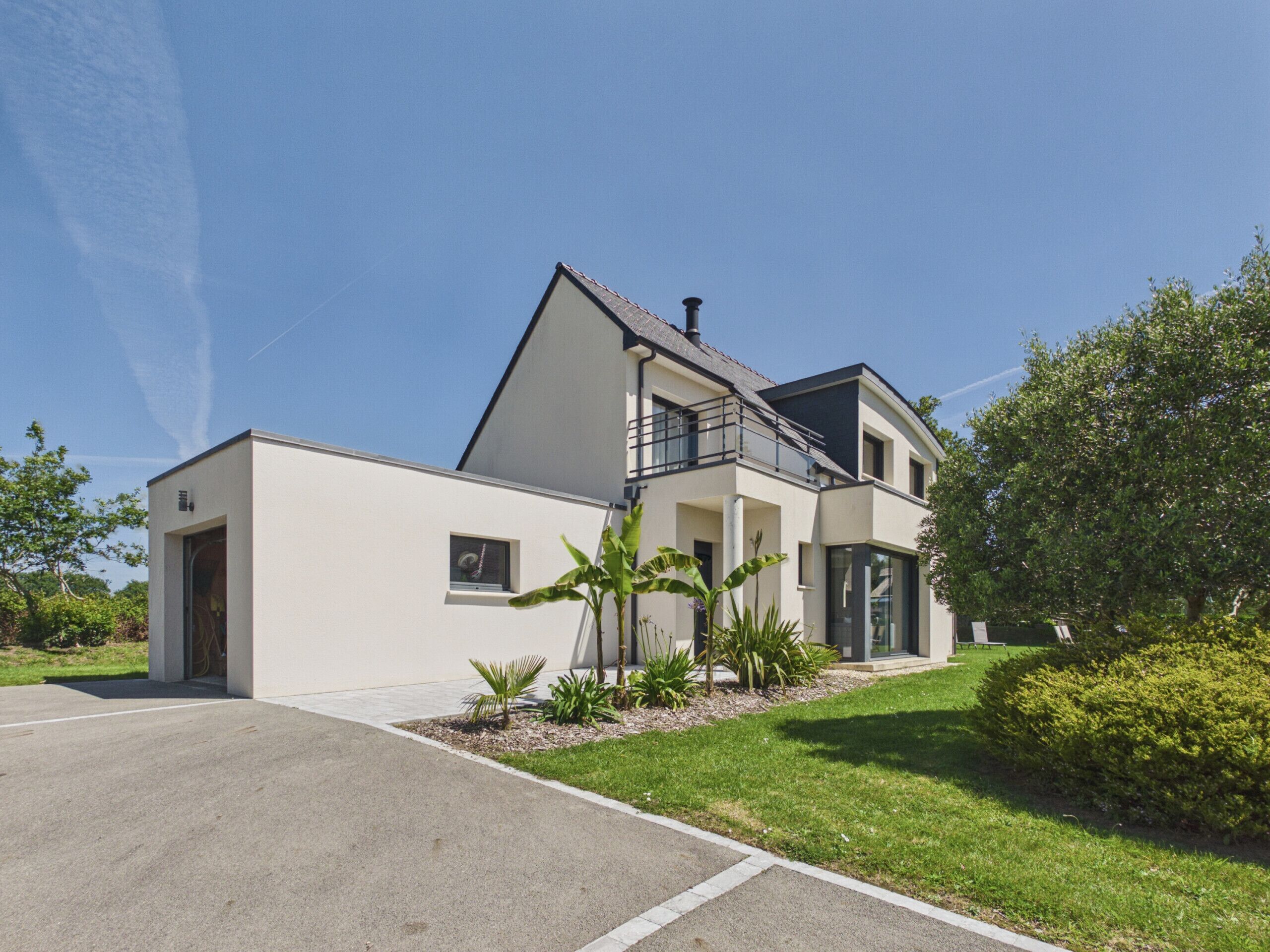 Een modern herenhuis met garage, balkon en een verzorgd gazon.