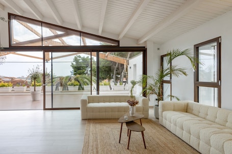 Un salon moderne avec un canapé, une table basse et une grande fenêtre.. Maison de vacances de luxe - Delmar Residences