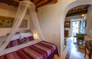 A bedroom with a bed, a canopy, a painting, a dining area with a table and chairs, and an archway leading to another room. - Awesome home in Sesto Fiorentino with sauna (Sesto Fiorentino)
