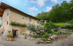 A stone building with a tiled roof, a door, and a small garden area with potted plants and a stone wall. - Awesome home in Sesto Fiorentino with sauna (Sesto Fiorentino)
