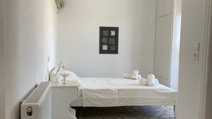 Une chambre à coucher avec un lit, un radiateur, une œuvre d’art encadrée au mur et un sol à motifs.