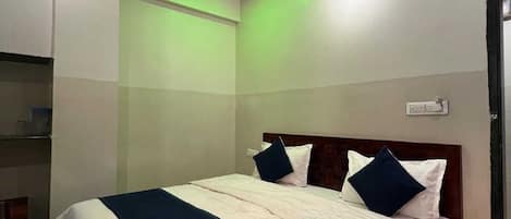 A bedroom with a bed, a ceiling fan, and a wall-mounted air conditioning unit.