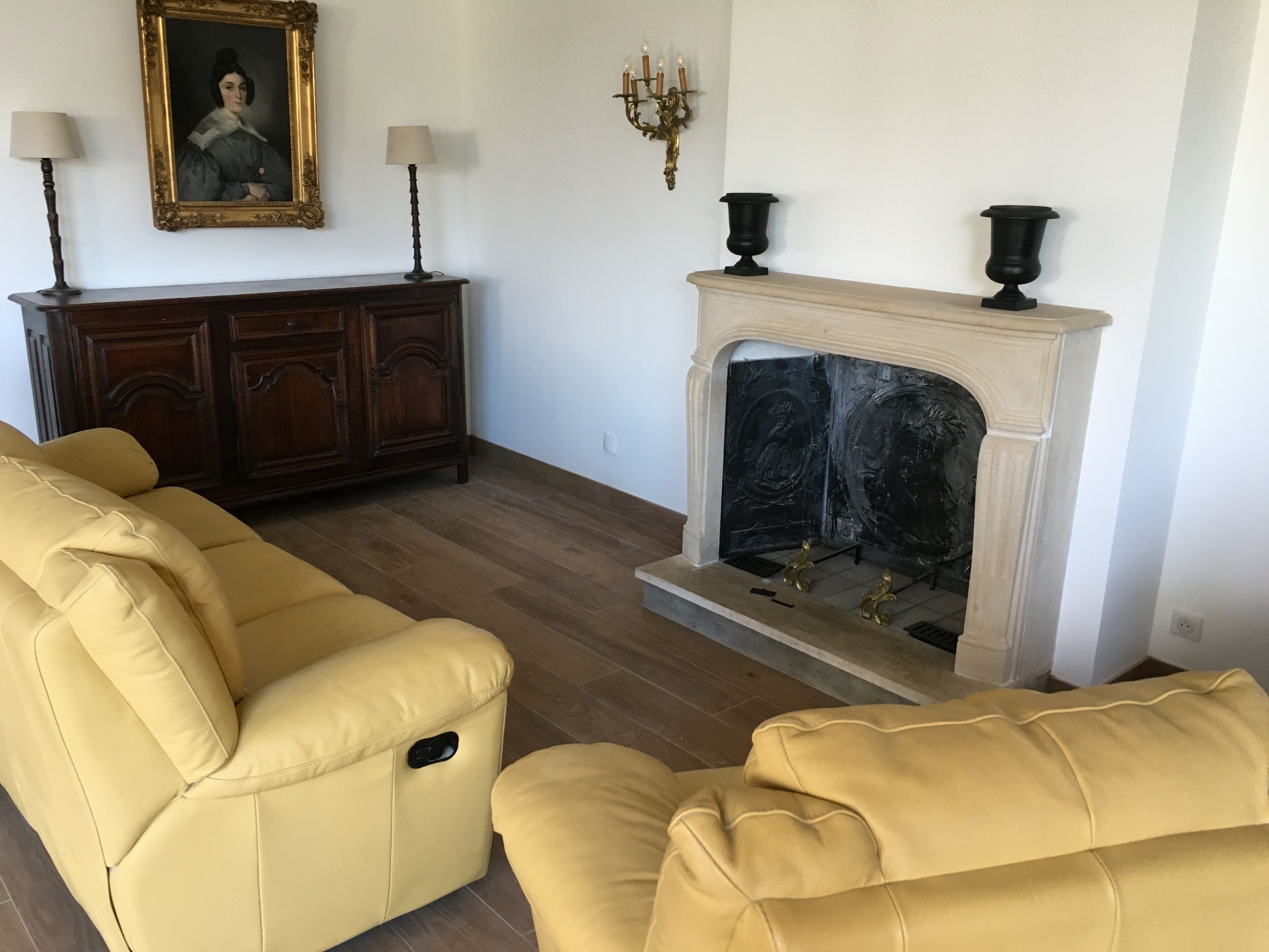 Una sala de estar con chimenea, un sofá, un armario y una lámpara de pared.