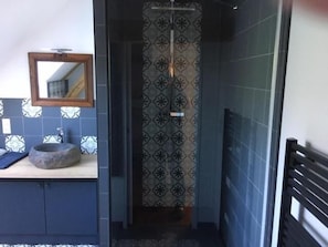 A bathroom with a sink, mirror, and patterned shower curtain.