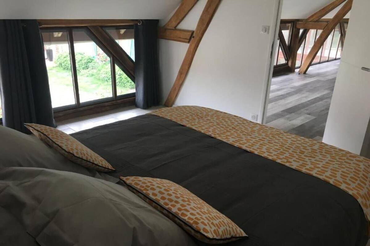 A bedroom with a large bed, a window with curtains, and a view of the outdoors.