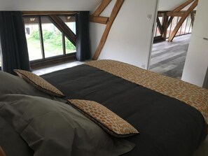 Un dormitorio con una cama grande, una ventana con cortinas y vistas al exterior.
