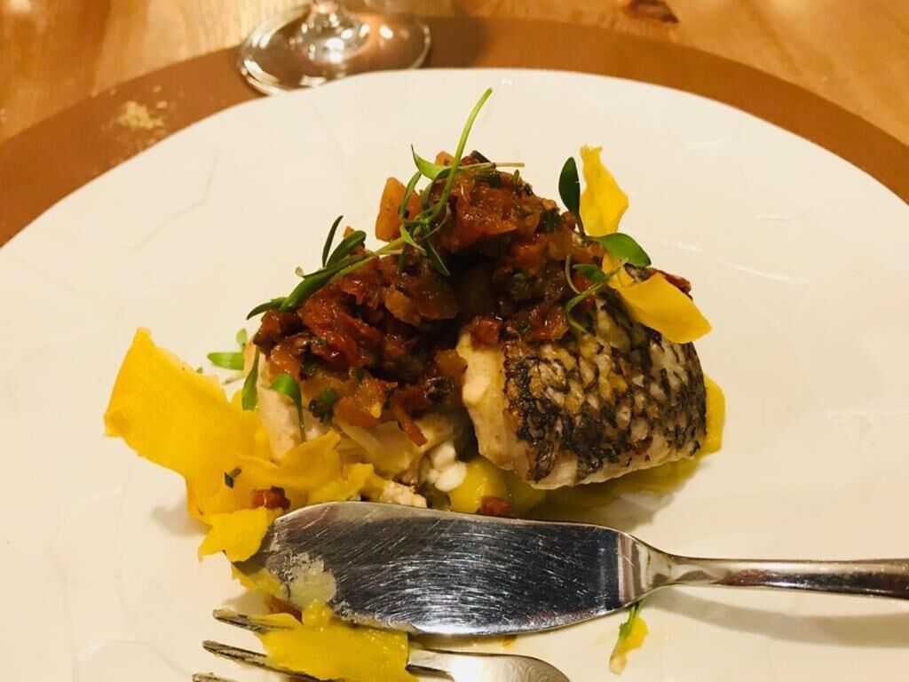 Ein weißer Teller mit Fisch, Gemüse und einer Gabel.