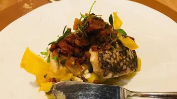 Ein weißer Teller mit Fisch, Gemüse und einer Gabel.