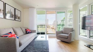 Ein modernes Wohnzimmer mit einer Couch, einem Sessel und einem Fernseher.
