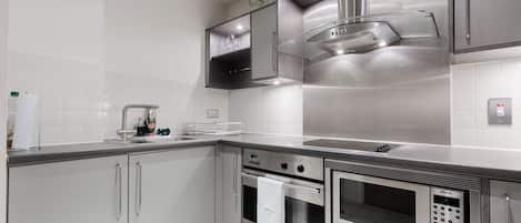 Una cocina moderna con electrodomésticos de acero inoxidable, horno empotrado y microondas.