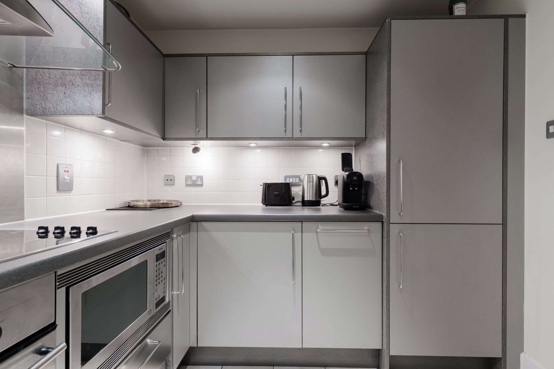 A modern kitchen with stainless steel appliances, white cabinetry, and a built-in oven.